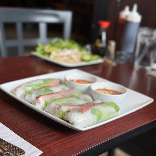 Vietnamese spring rolls with dipping sauces on a white rectangular plate at What The Phở.